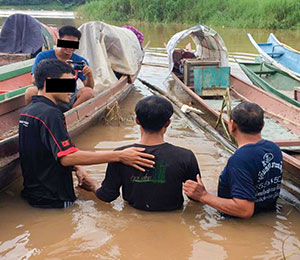 Two men baptizing a woman in a small pool